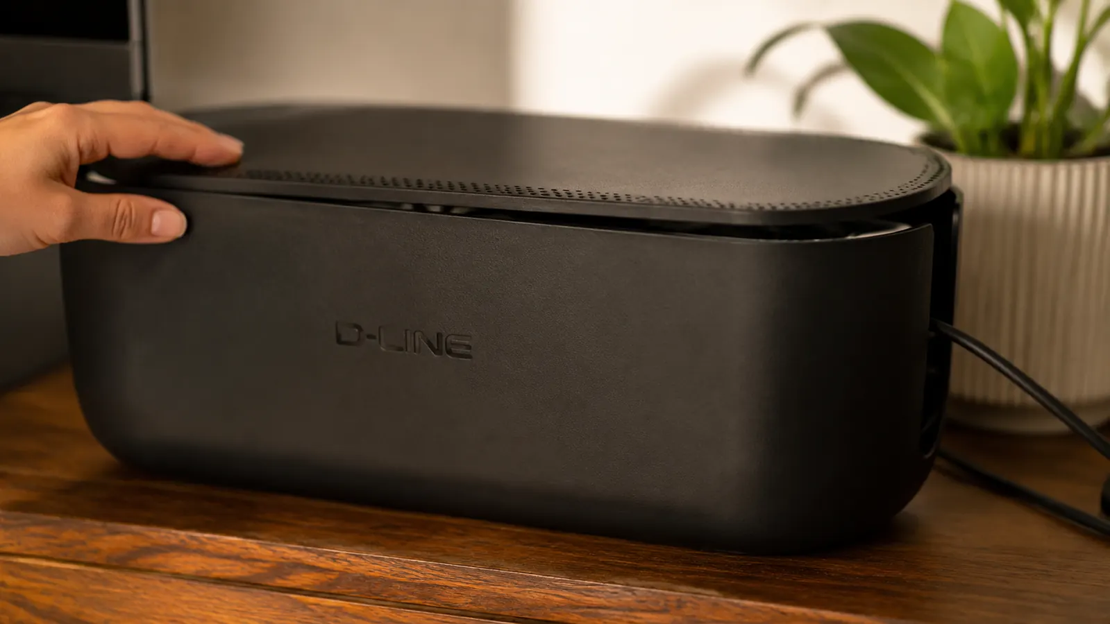 Close-up of the D-Line cable box lid sitting slightly raised on one side due to a bulky power adapter inside