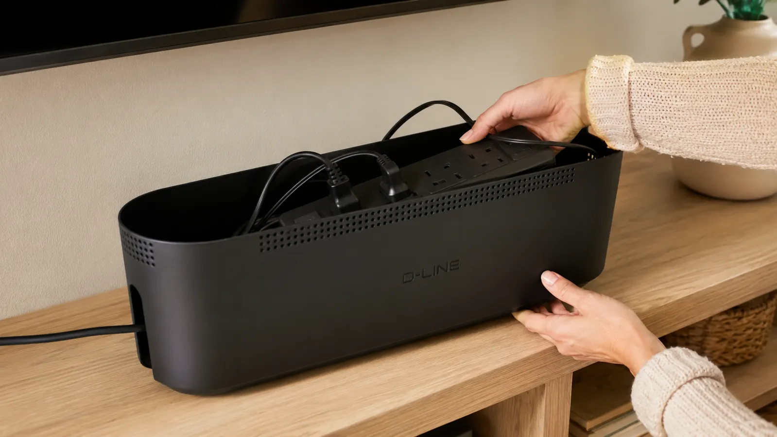 Hand placing a power strip inside an open D-Line cable management box before closing the lid